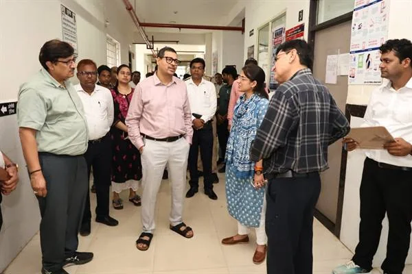 अस्पताल के गलियारे में खड़े अधिकारी और स्वास्थ्यकर्मी आपस में चर्चा करते हुए