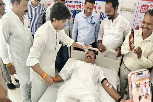 अस्पताल के बिस्तर पर रक्तदान करते व्यक्ति के पास खड़े ज्योतिरादित्य सिंधिया और अन्य लोग